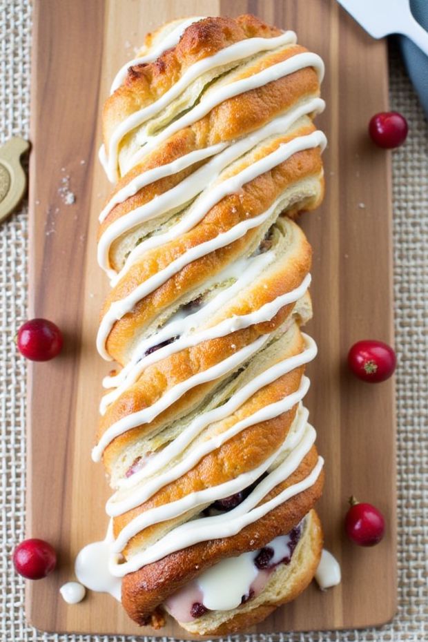 Festive braided cranberry orange puff pastry with white icing and fresh cranberries, perfect for holiday celebrations.