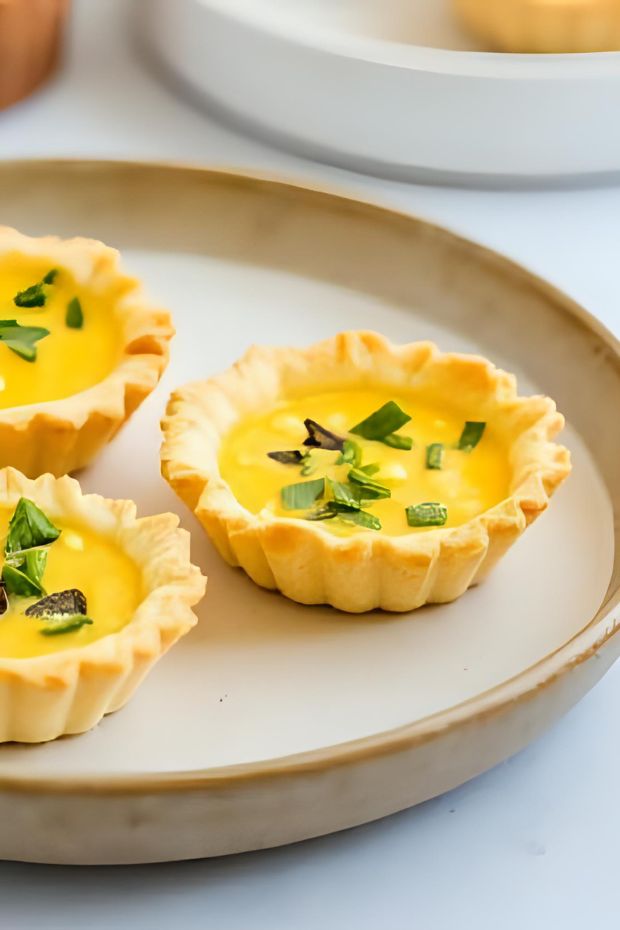 Savory mini tarts filled with sweet corn and basil custard, perfect for appetizers or gatherings.