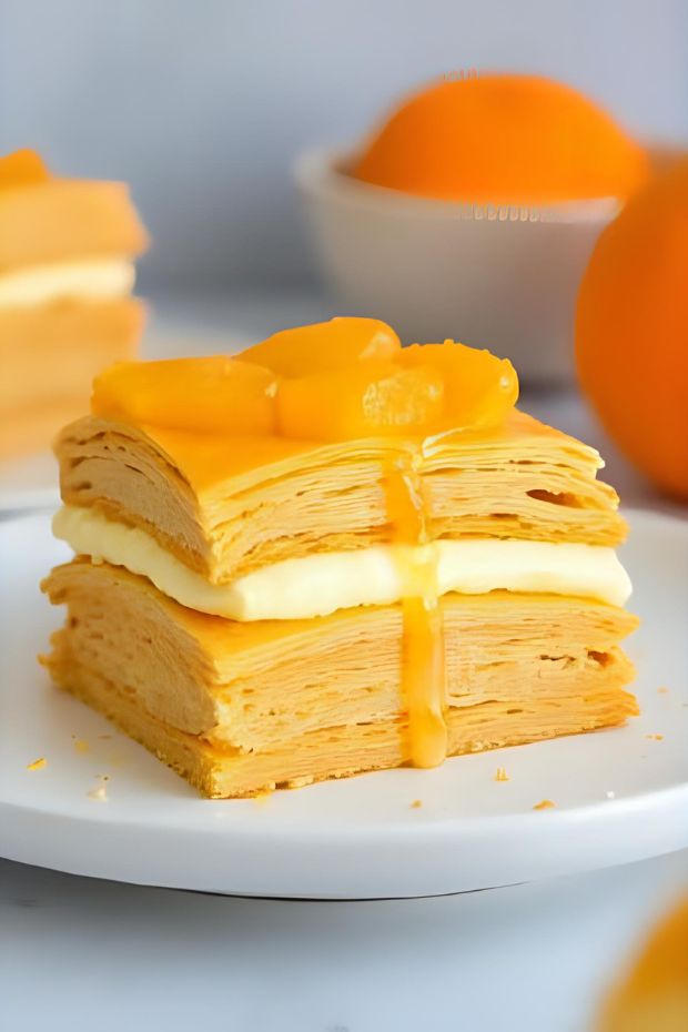 A beautiful Zesty Orange Cream Mille-Feuille, showcasing layers of puff pastry and creamy orange filling.