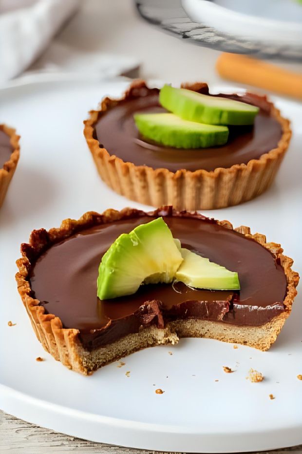 Plant-based vegan chocolate avocado tarts with mint garnish, rich chocolate filling and crispy shell.